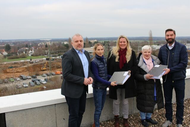 Grünes Licht für den Baustart auf der Viktoria-Brache (zu sehen im Hintergrund): Bürgermeister Dirk Wigant (l.), Claudia Senge (Bauordnung, 2. v. l.) und der Erste Beigeordnete Jens Toschläger überreichten die Baugenehmigung an Karin Rose (M., Geschäftsführerin der Viktoria Grundstücks GmbH & Co. KG) sowie an Marianne Oldenberg (stellvertretende Geschäftsführerin des Jobcenters Kreis Unna).
