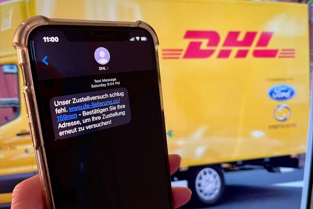 Ein Handy mit der Fake-DHL-Text-Nachricht wird vor einen DHL-Lieferwagen gehalten.
