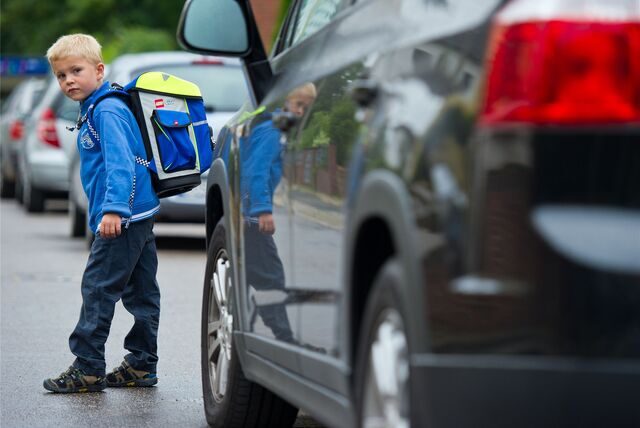 Ein Junge mit Schulranzen überquert eine Straße.