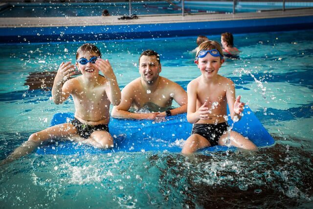 Kinder mit ihrem Vater im Schwimmbecken