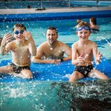 Kinder mit ihrem Vater im Schwimmbecken