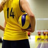 Eine Volleyballspielerin hält den Ball unterm Arm.