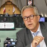 Im Vordergrund Dortmunds Polizeipräsident Gregor Lange, in den Hintergrund ist ein Blick ins iranische Parlament montiert.