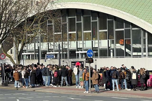 Eine große Menschenmenge steht auf dem Platz vor dem Theater. Ein anliegendes Gebäude wurde wegen eines Feuerwehreinsatzes geräumt.