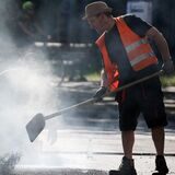 Zwei Arbeiter asphaltieren eine Straße.