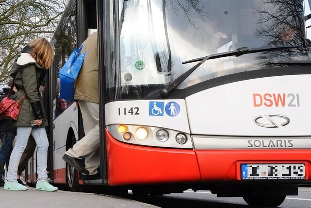 Menschen steigen in einen Bus ein.