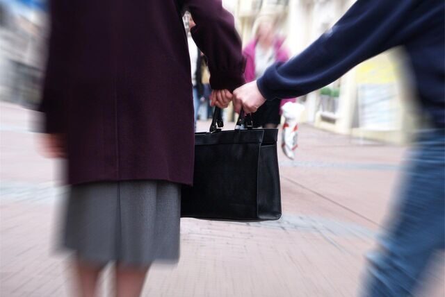 Jemand greift nach der Handtasche einer Frau.