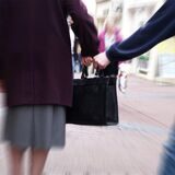 Jemand greift nach der Handtasche einer Frau.