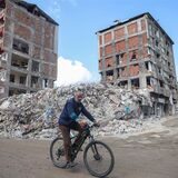 Ein Mann fährt mit dem Fahrrad an zerstörten Gebäuden entlang.