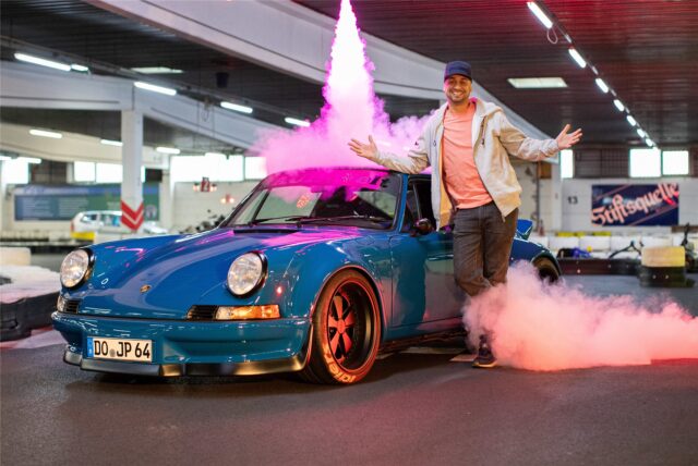 JP Kraemer vor blauem Auto und Feuerwerk