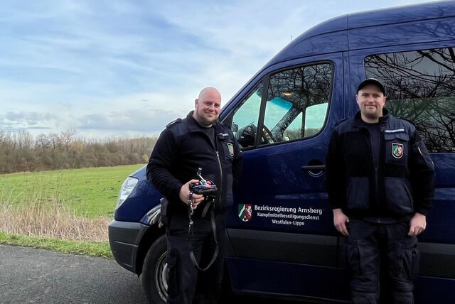 Allessandro Rammeter und Justin Finke vom Kampfmittelräumdienst der Bezirksregierung Arnsberg sprengten die gefundene Granate kontrolliert auf der Wiese im Hintergrund.