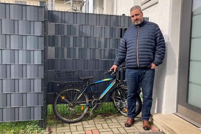 Fadi El-Jaddouh, der Vater des bei einem Zugunglück in Recklinghausen schwer verletzten Neunjährigen, steht vor einem Haus neben dem Fahrrad seines Sohnes.