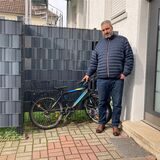 Fadi El-Jaddouh, der Vater des bei einem Zugunglück in Recklinghausen schwer verletzten Neunjährigen, steht vor einem Haus neben dem Fahrrad seines Sohnes.
