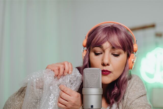 frau nimmt einen asmr podcast auf und knistert dafür mit folie vor einem mikrofon