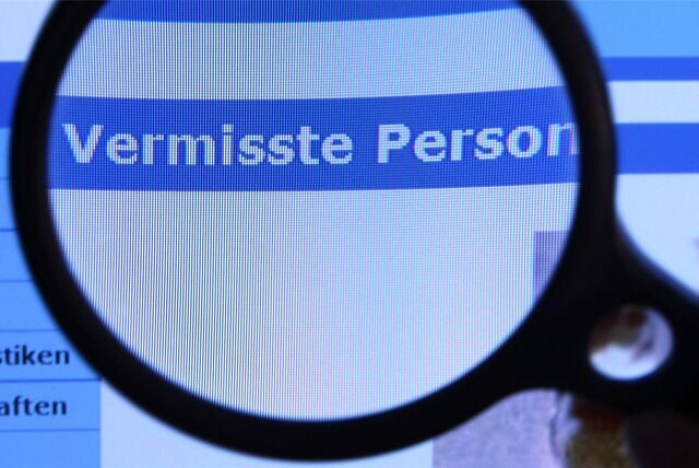 Foto einer Lupe, die auf einem Bildschirm über dem Schriftzug „Vermisste Person“ hält.