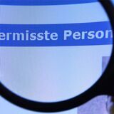 Foto einer Lupe, die auf einem Bildschirm über dem Schriftzug „Vermisste Person“ hält.