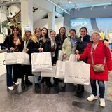 Neun Frauen stehen mit Einkaufstüten im Modehaus Heckmann.