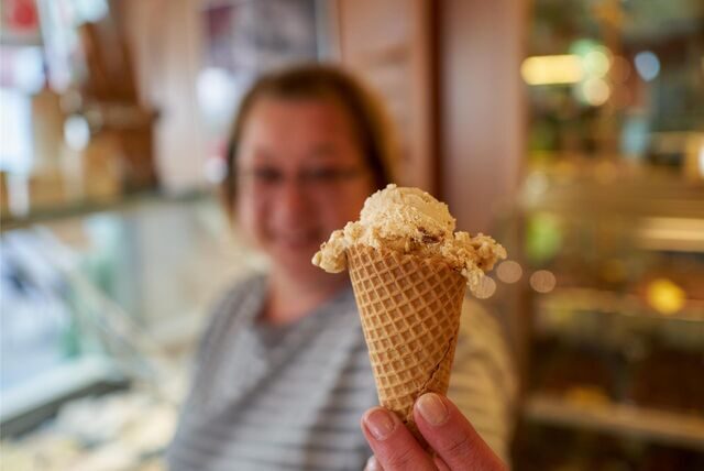 Eine Frau hält eine Eistüte in die Kamera