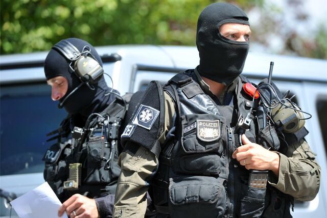 Maskierte Polizisten eines Sondereinsatzkommandos sichern am 11.07.2014 in Asbach-Bäumenheim (Bayern) ein Grundstück.