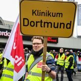 „Klinikum Dortmund“ steht auf einem Schild, das ein Mann hochhält.