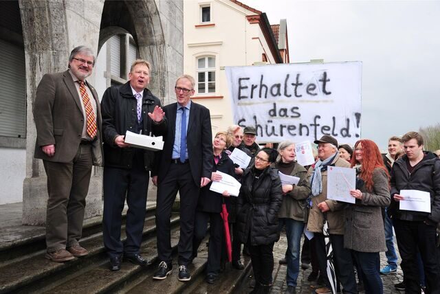Viele Menschen mit einem Plakat auf dem „Erhaltet das Schürenfeld“ steht stehen vor dem Fröndenberger Rathaus. Zu sehen sind außerdem Andreas Hennemann, Initiator der Bürgerinitiative, und der damalige Bürgermeister Fritz Rebbe.