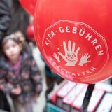 Ein Luftballon mit der Aufschrift „Kitagebühren abschaffen“ bei einer Demo (Symbolfoto). In NRW sind die beiden letzten Kitajahre beitragsfrei. Ministerpräsident Hendrik Wüst hat im Wahlkampf 2022 ein drittes beitragsfreies Jahr versprochen.