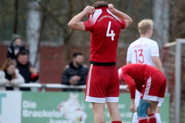 Fußballspieler vergräbt seinen Kopf im Trikot nach einem Gegentor.