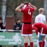 Fußballspieler vergräbt seinen Kopf im Trikot nach einem Gegentor.