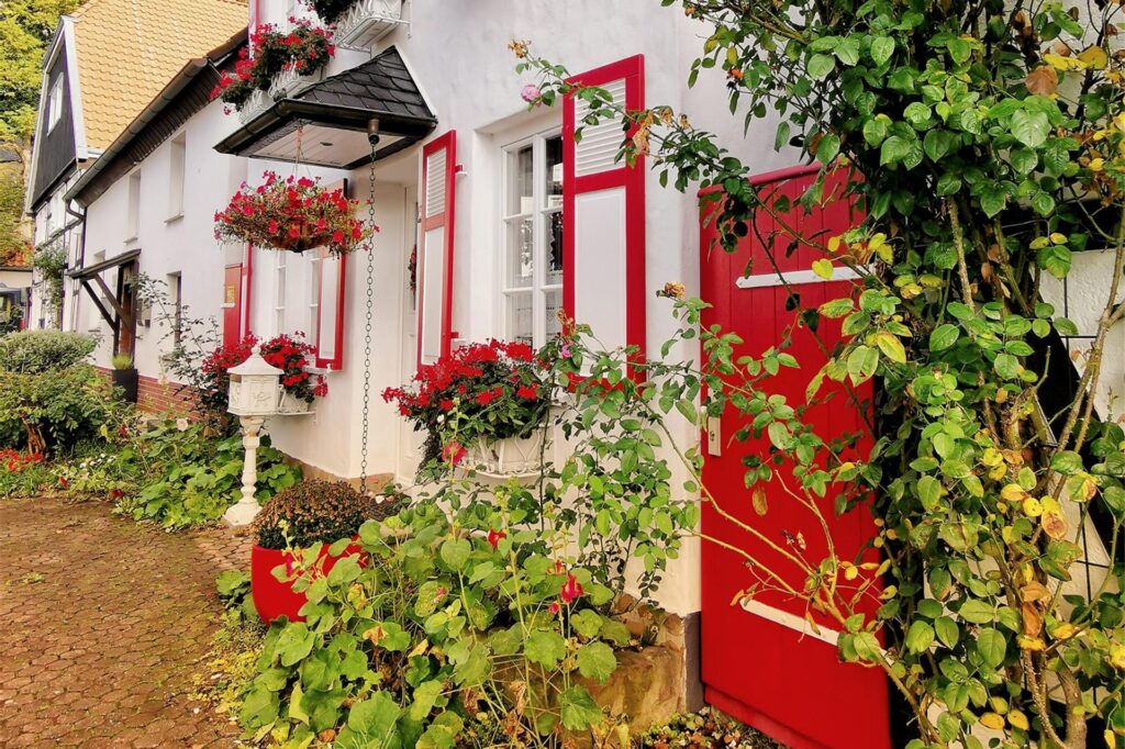 Zu sehen ist ein Haus mit einer roten Tür und roten Fensterläden.
