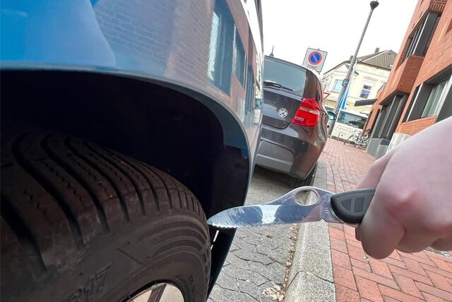 Ein Taschenmesser wird an einen Autoreifen gehalten.