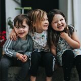 Drei Kinder sitzen nebeneinander und haben Spaß.