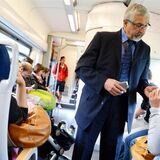 Ein Fahrkartenkontrolleur steht in einer Bahn und kontrolliert Fahrscheine.