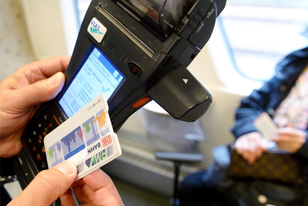 Mit einem mobilen Terminal überprüft ein Fahrkarten-Kontrolleur die Bahnkarte eines Fahrgastes. Mit einem mobilen Terminal überprüft ein Fahrkarten-Kontrolleur die Bahnkarte eines Fahrgastes.