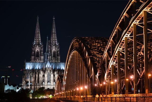 Der Kölner Dom und die Hohenzollernbrücke beleuchtet bei Nacht.