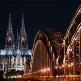 Der Kölner Dom und die Hohenzollernbrücke beleuchtet bei Nacht.