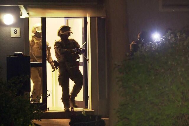 Schwer bewaffnete Polizisten verlassen ein Haus.