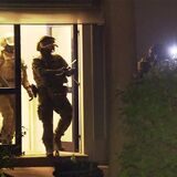 Schwer bewaffnete Polizisten verlassen ein Haus.