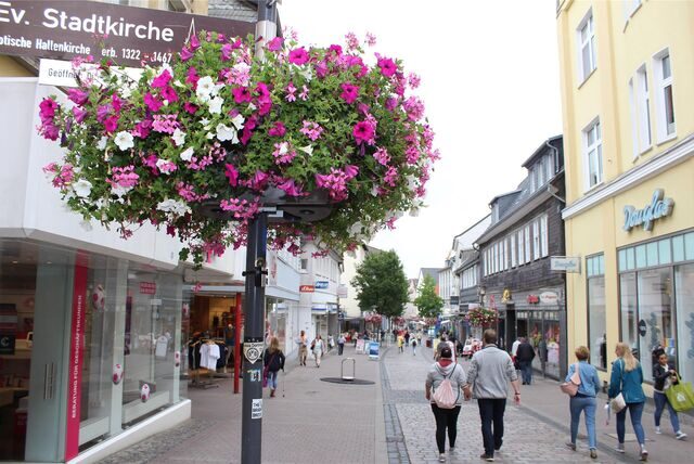 Ein üppig blühender Pflanzkorb mit Geranien und Petunien schmückt an einem Laternenmasten die Bahnhofstraße in der Unnaer Fußgängerzone.