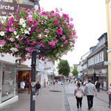 Ein üppig blühender Pflanzkorb mit Geranien und Petunien schmückt an einem Laternenmasten die Bahnhofstraße in der Unnaer Fußgängerzone.