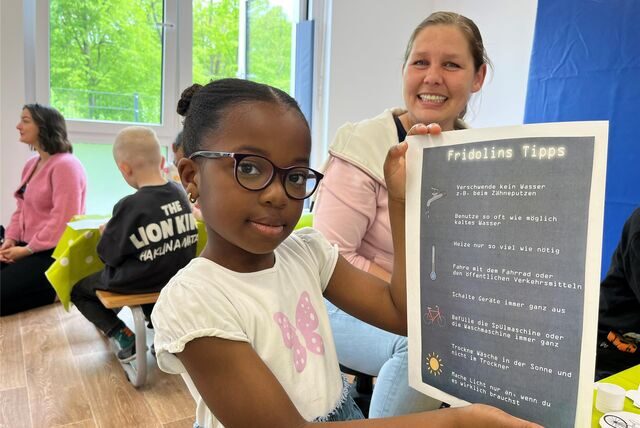 Makanfi (5) klebt eine Liste auf, die sie mit nach Hause nimmt, um zu zeigen, wie man Energie sparen kann.
