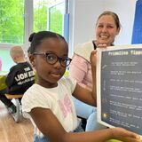Makanfi (5) klebt eine Liste auf, die sie mit nach Hause nimmt, um zu zeigen, wie man Energie sparen kann.