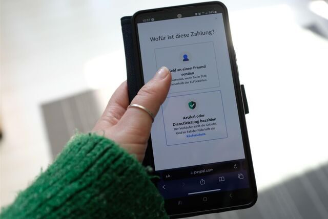 Auf einem Handy-Display ist die Frage „Wofür ist diese Zahlung?“ zu sehen.