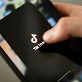 Ein Teenager tippt auf das TikTok-Logo auf einem Smartphone.