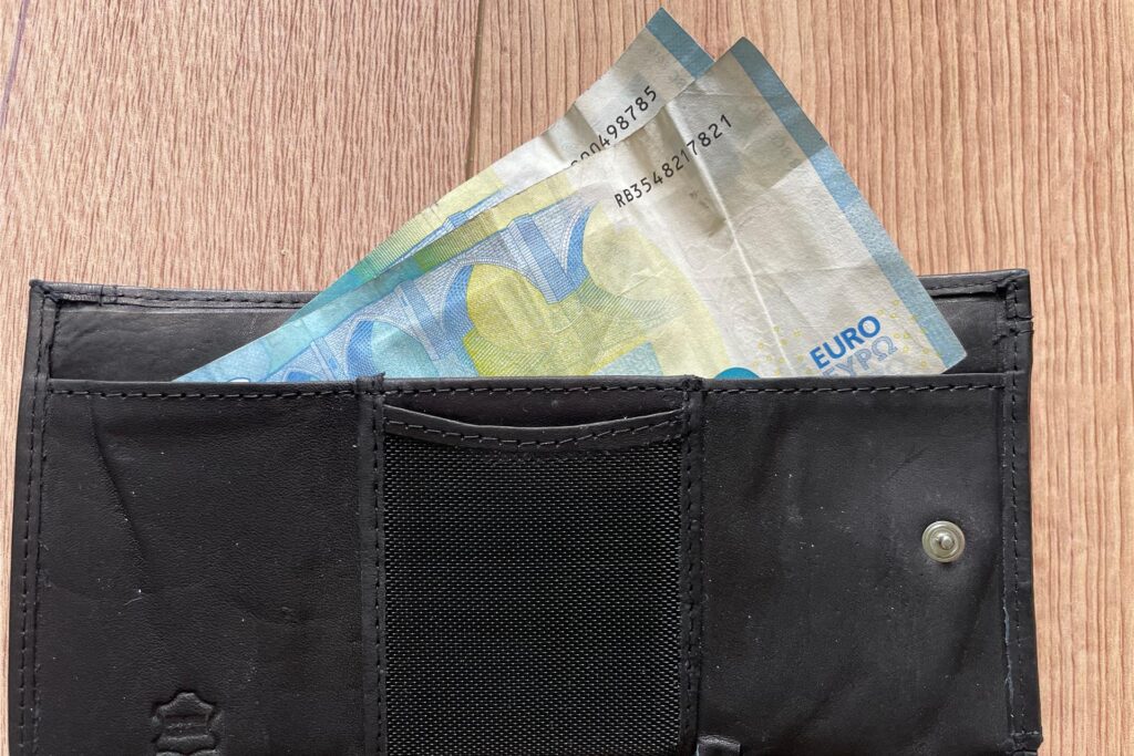 Zwei Geldscheine ragen aus einem Portemonnaie heraus.