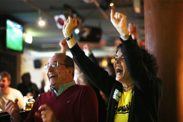 Zwei BVB-Fans stehen jubelnd in einer Kneipe.
