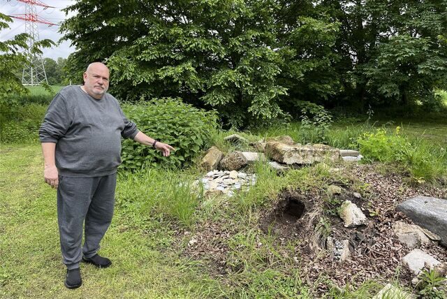 Gerhard Lungmus zeigt auf den unkrautüberwucherten Bauschutt-Haufen am Friedhof.