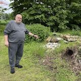 Gerhard Lungmus zeigt auf den unkrautüberwucherten Bauschutt-Haufen am Friedhof.