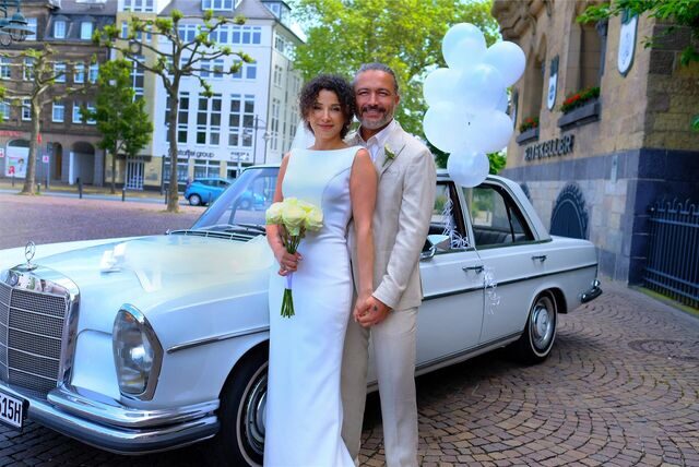 Das Brautpaar Sibel Özel und Bünyamin Altun vor einer Mercedes-Limousine.