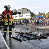 Zu sehen sind Feuerwehrmänner bei einer Schauübung. Viele Kinder und Erwachsene schauen zu.