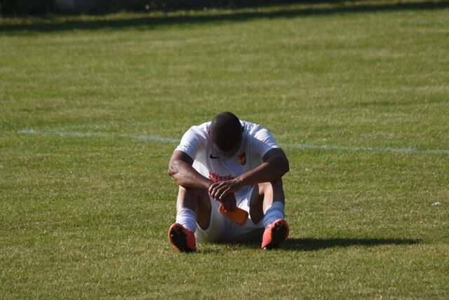 Ein Roj-Spieler sitzt enttäuscht auf dem Rasen.
